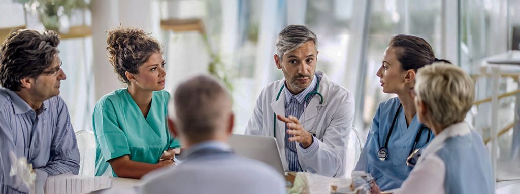 Um grupo de profissionais da saúde conversa em uma reunião. Programa de Compliance: 6 Dicas para Implantar em Clínicas e Consultórios.
