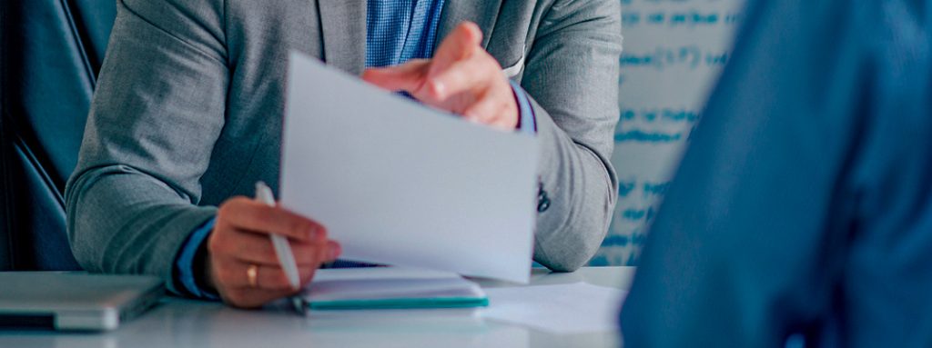Um homem de terno analisa documentos. O que é Outsourcing e Como Ele se Aplica aos Negócios de Saúde.