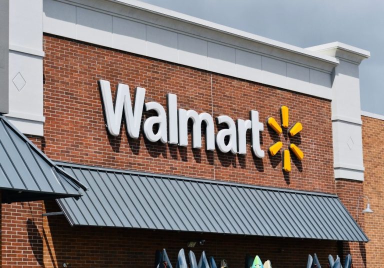 Uma fachada de loja com o letreiro "Walmart" e sua estrela amarela em um prédio de tijolos. Curso: Aprenda com Sam Walton.