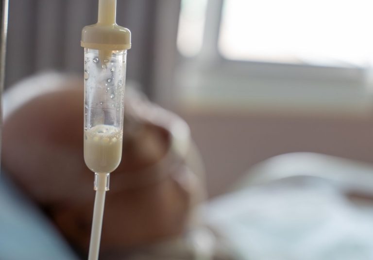 Alimentação pendurada em um suporte, conectada a um paciente em uma cama hospitalar. Curso: Dietoterapia.