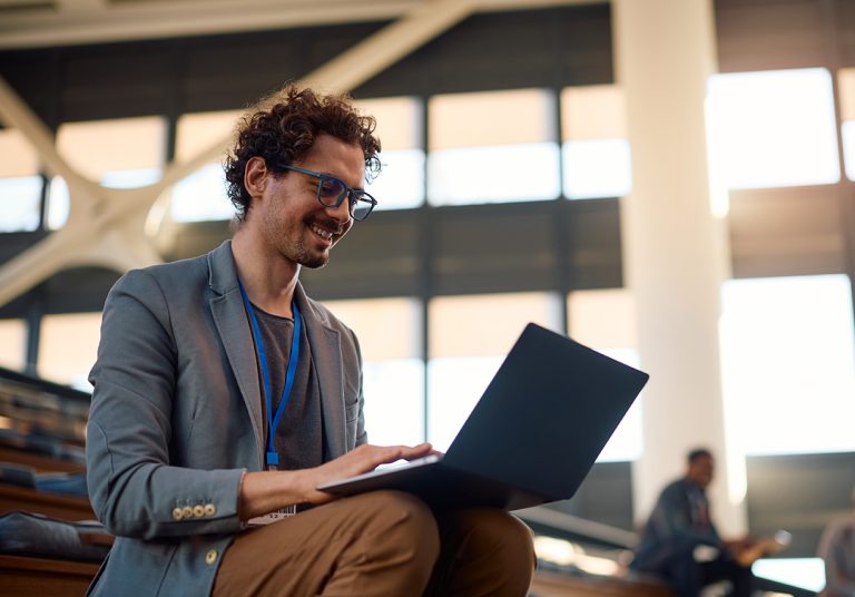 Homem, especialista formado no MBA em Proteção de Dados, Privacidade e Novas Tecnologias Aplicadas à Saúde. Ele olha para um notebook sobre as pernas em um ambiente moderno.