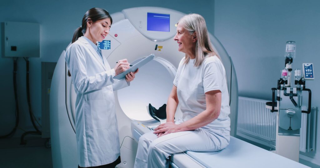 Uma profissional da saúde conversa com uma paciente idosa em um hospital. Curso: Oncologia Multiprofissional