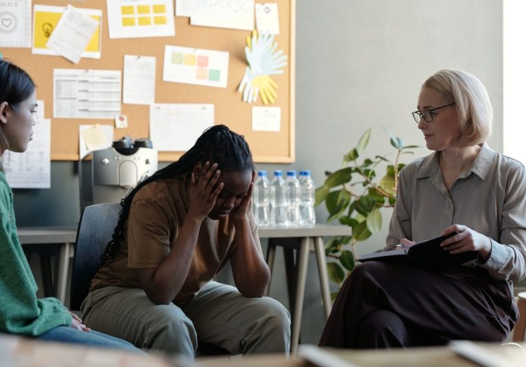Mulher com as mãos na cabeça, em sessão com terapeuta. Curso: Trilha de Aprendizagem: Saúde Mental.