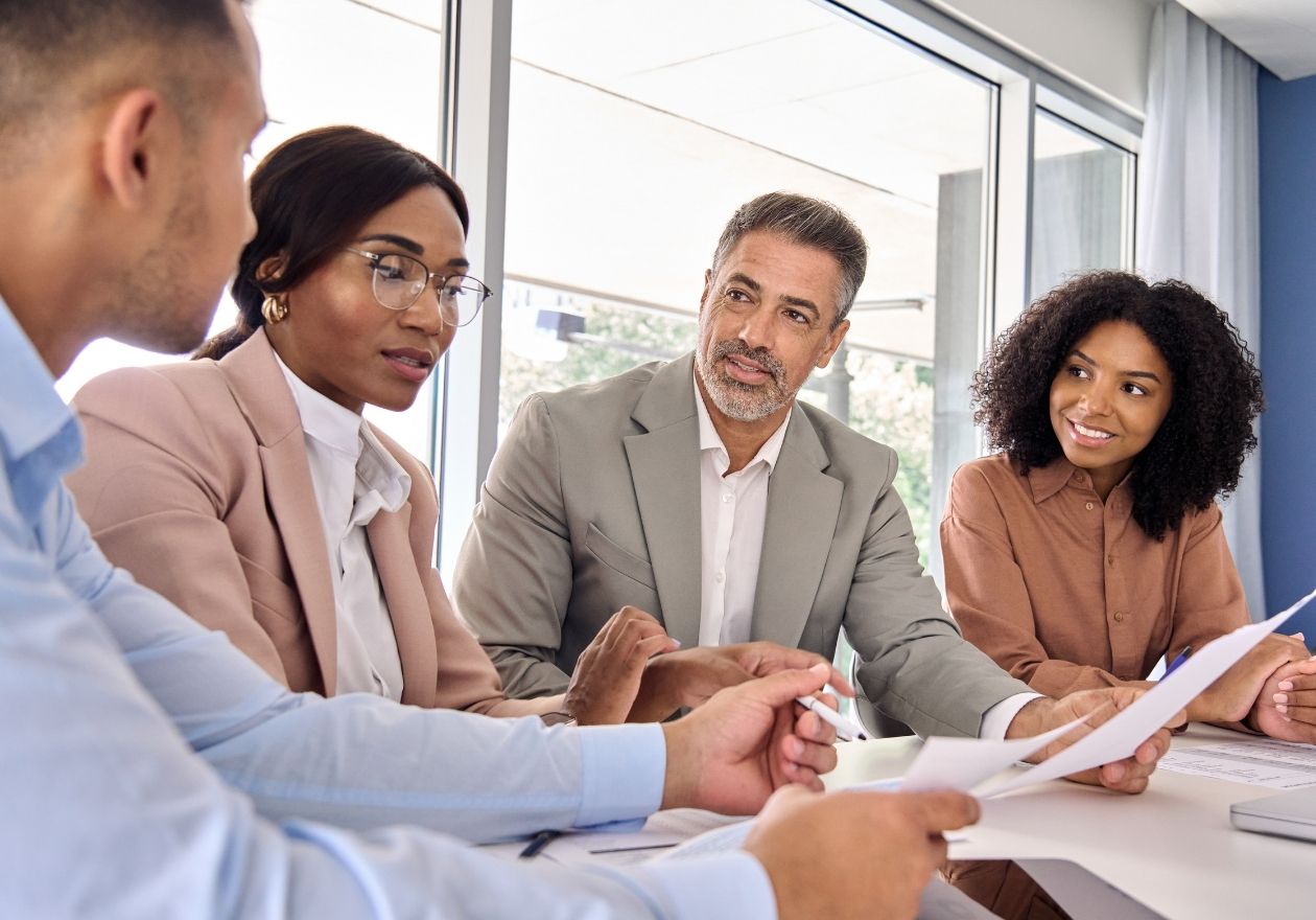 Quatro pessoas discutem em uma reunião. Curso: Formação de Auditor Interno para Sistemas de Gestão da Qualidade (ISO 19011:2018)