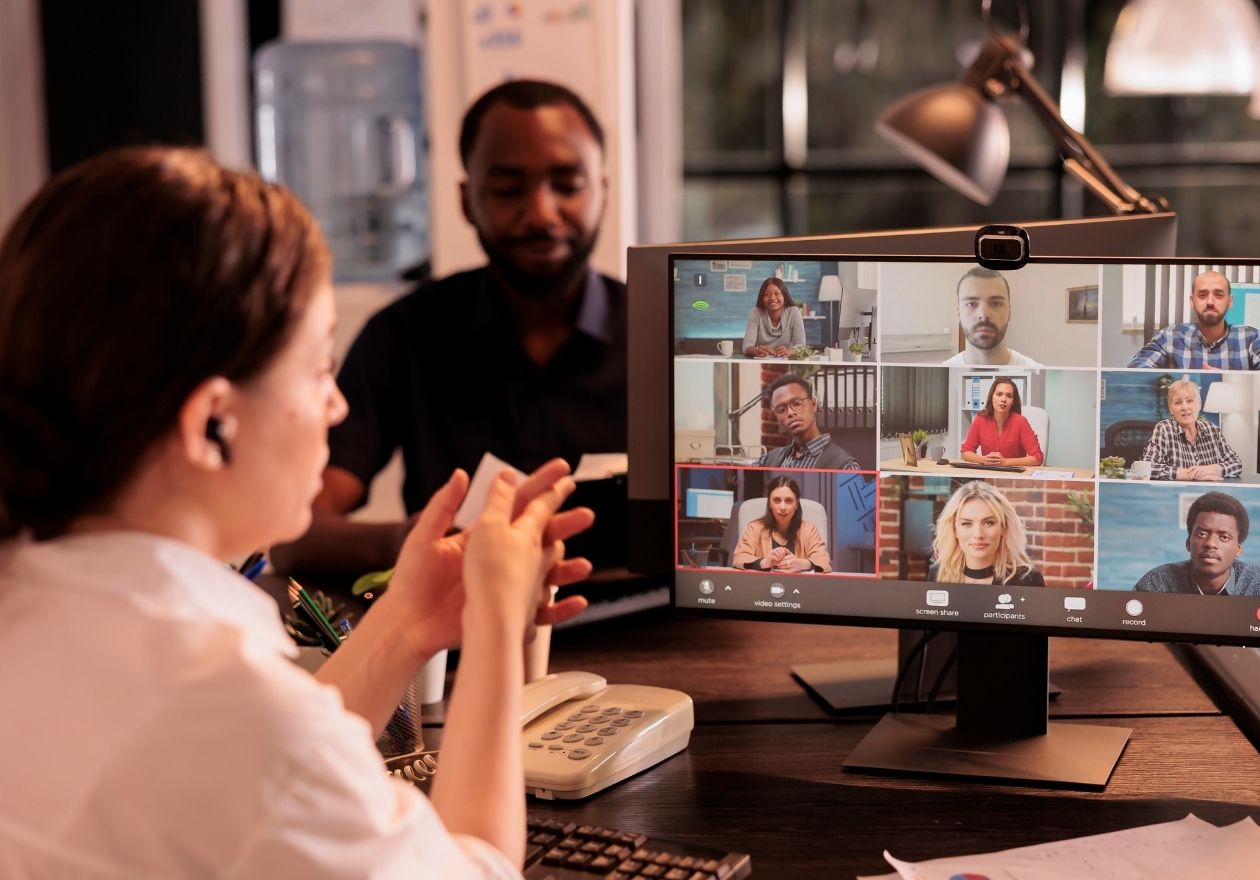 Um grupo de pessoas participa de uma videoconferência em um escritório. Curso: Gerenciando Times Virtuais de Alta Performance.
