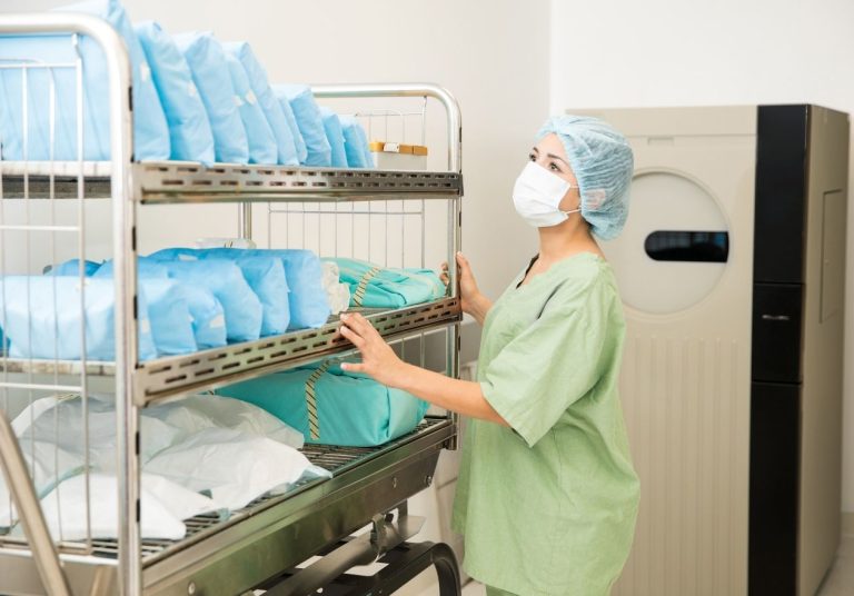 Profissional organiza pacotes esterilizados em prateleiras, em ambiente médico. Curso: Gestão da Segurança Institucional.