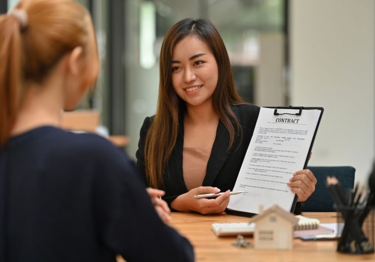 Profissional com prancheta conversa com cliente na recepção. Curso: Lidar com Clientes Nervosos.
