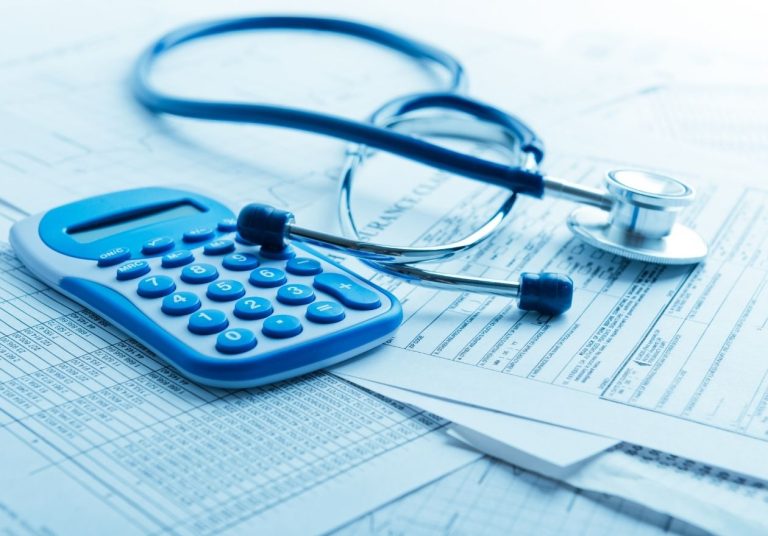 Estetoscópio e calculadora azul sobre papéis. Curso: Regulação dos Planos de Saúde - Reajustes.