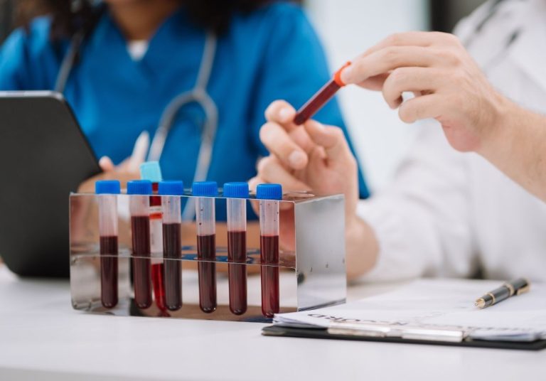 Profissionais da saúde manipulando tubos de ensaio com sangue. Curso: Tipos Sanguíneos.