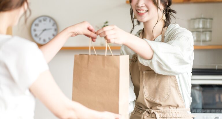 A,Female,Cafe,Attendant,Handing,Out,Takeout,Items,To,Customers