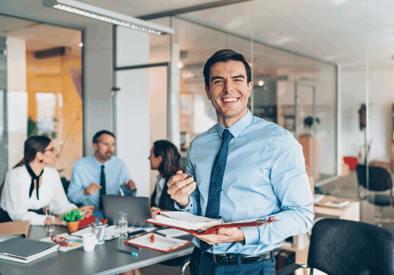 Homem em destaque, com um fundo desfocado com o restante da equipe corporativa discutindo o planejamento estratégico